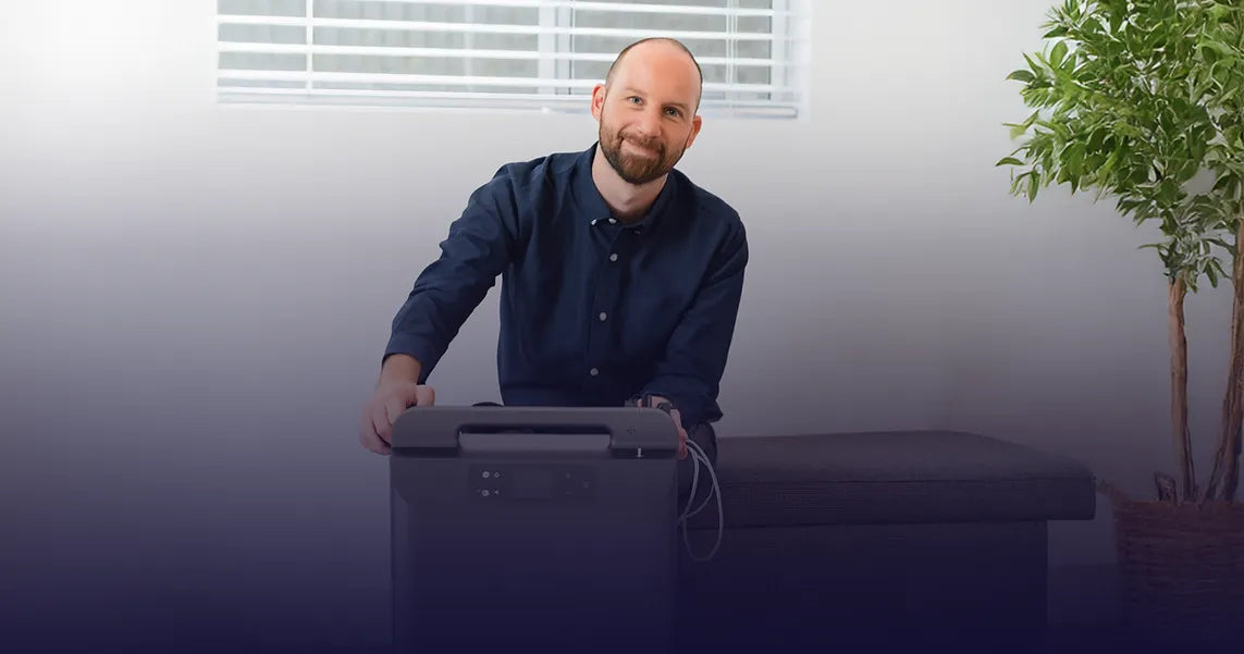 A man that looks like a son smiling while next to a Kingon P2-O5E stationary oxygen concentrator.
