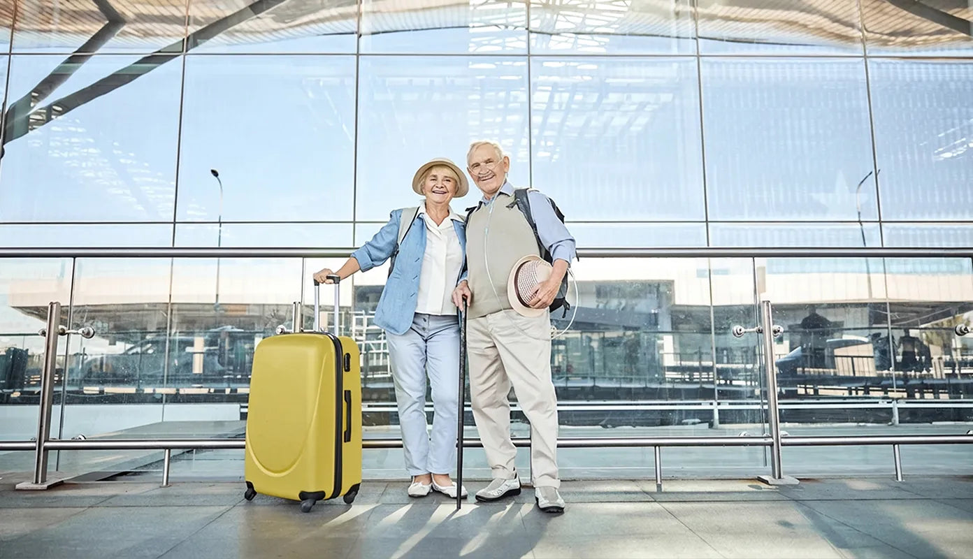 Old couple in airport, one is using a nasal cannula.