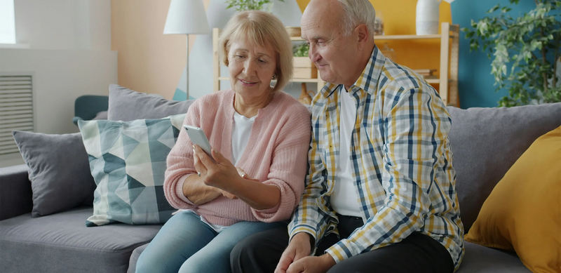 An old woman and man looking at a phone together while smiling.