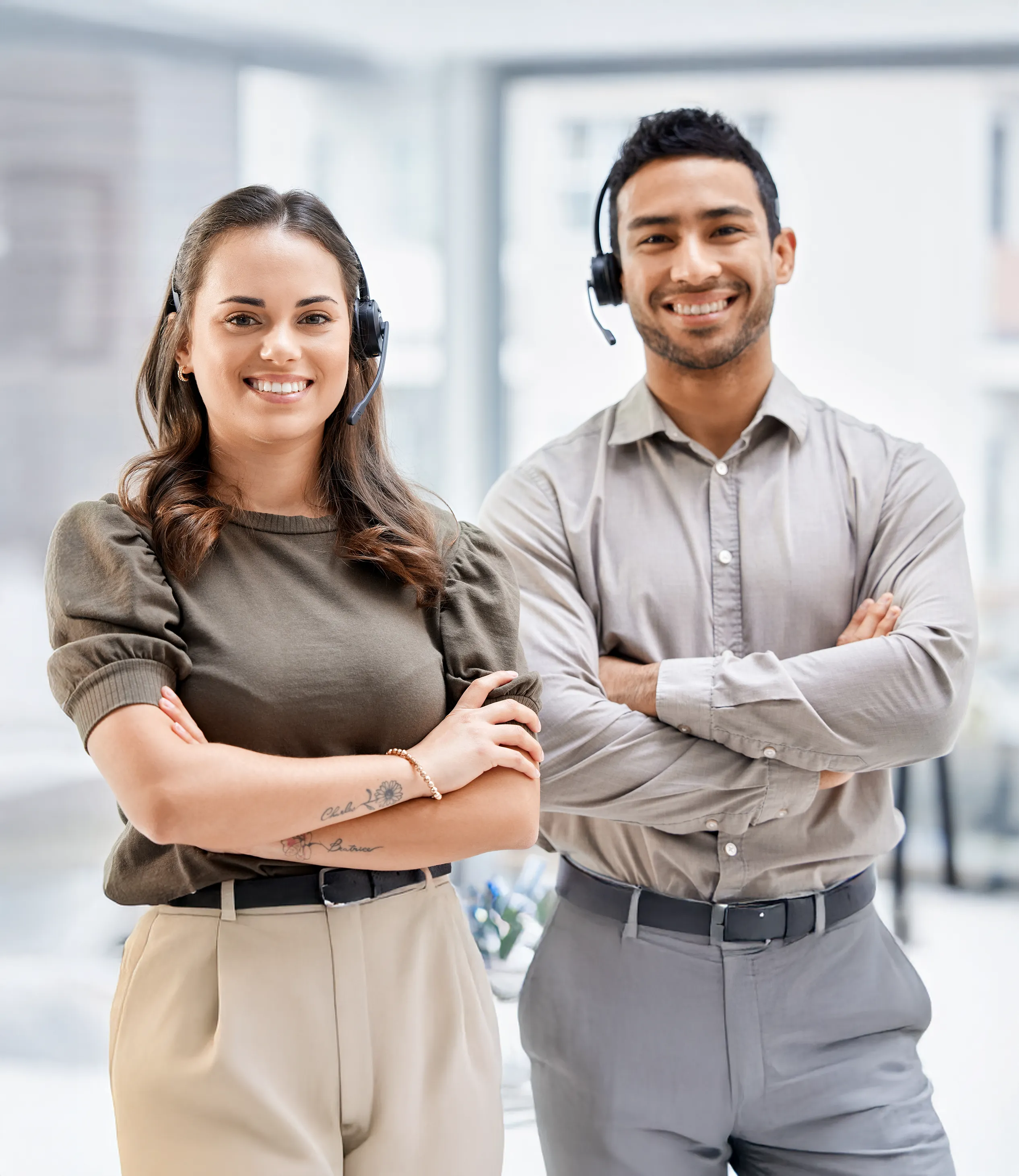 Two service agents smiling with their arms crossed in the office.